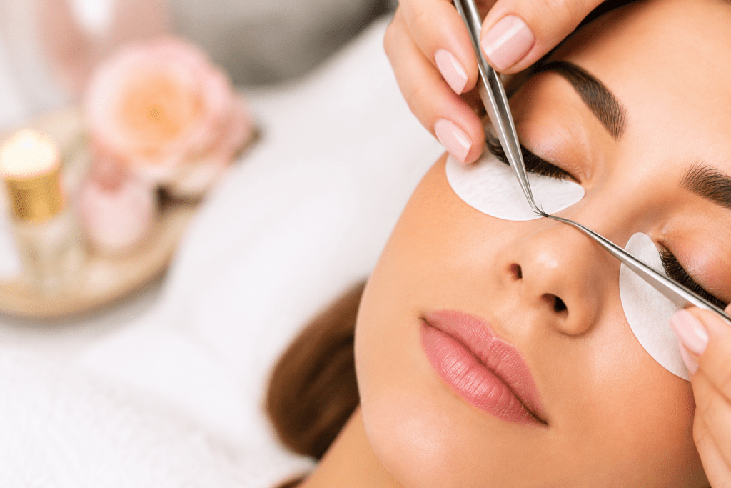 Professional lash technician applying affordable eyelash extensions to a client in a clean beauty salon.